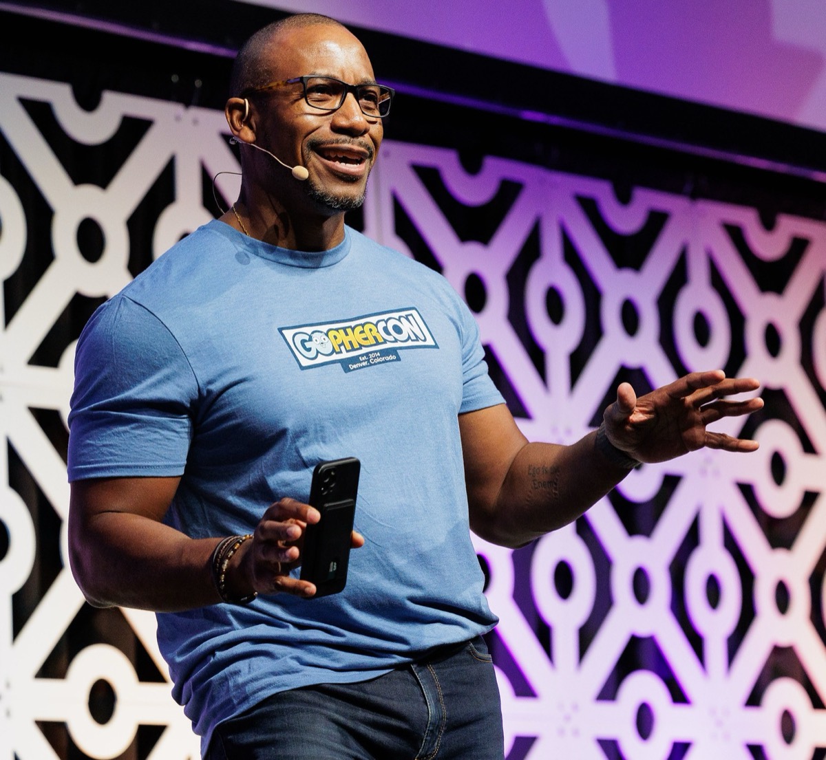 Johnny speaking into a headset mic on the GopherCon stage, gesturing with one hand