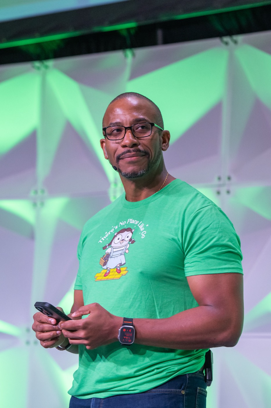 Johnny on stage in a green GopherCon shirt
