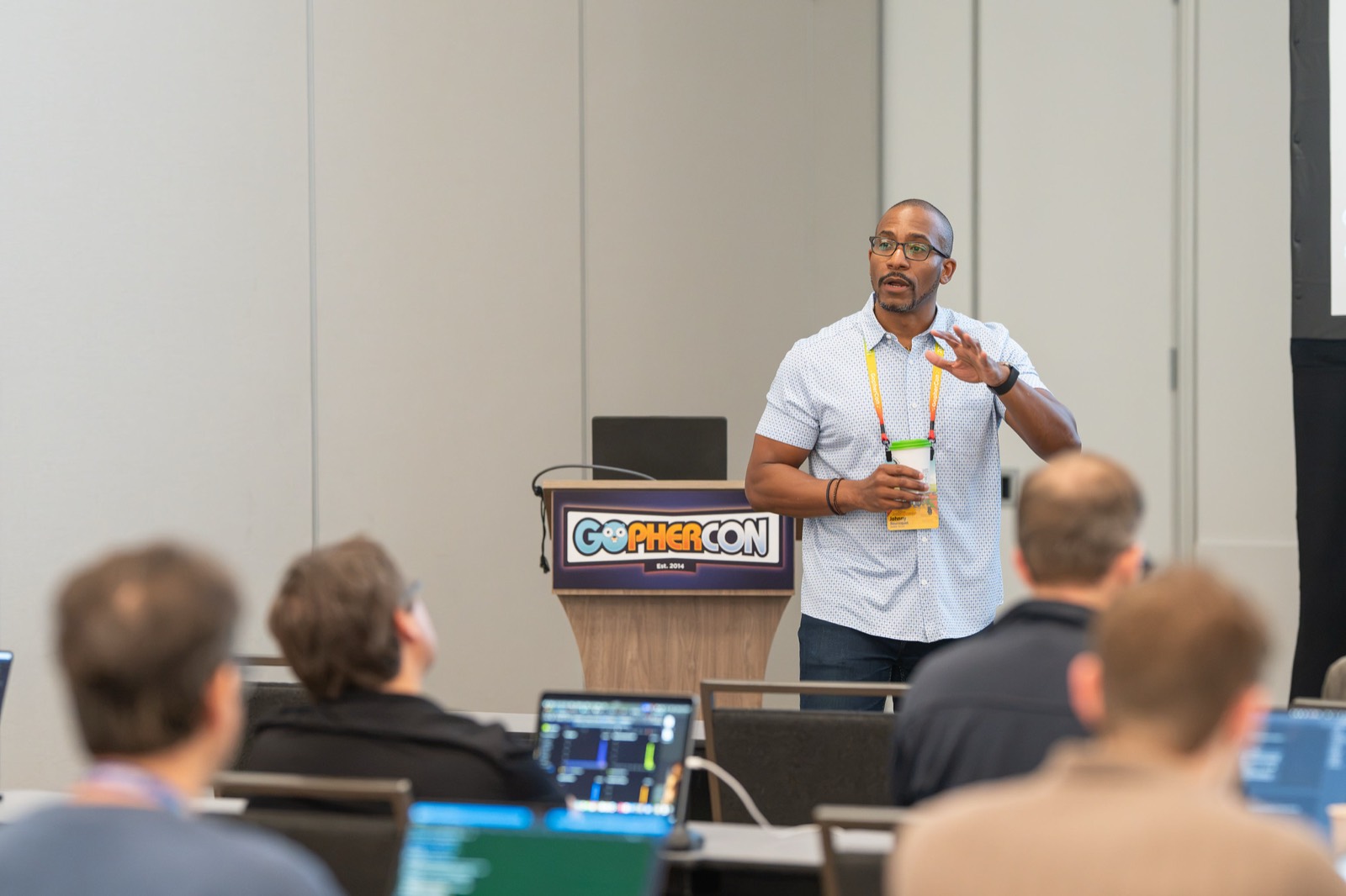 Johnny teaching at the front of a workshop room, attendees at laptops in the foreground