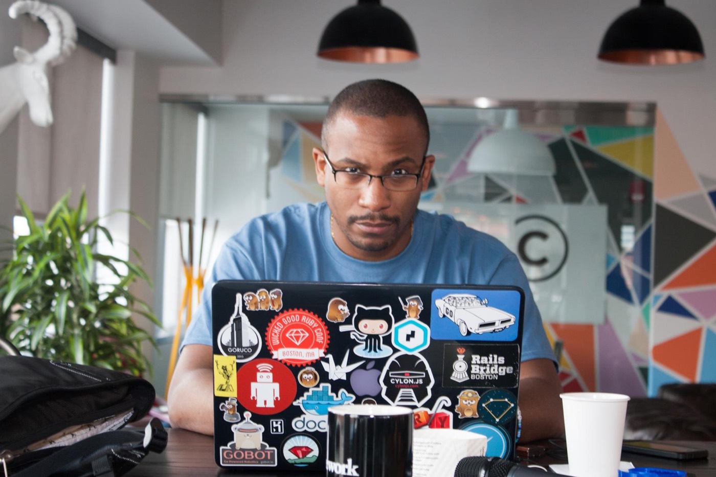 Johnny working at a laptop covered in developer stickers